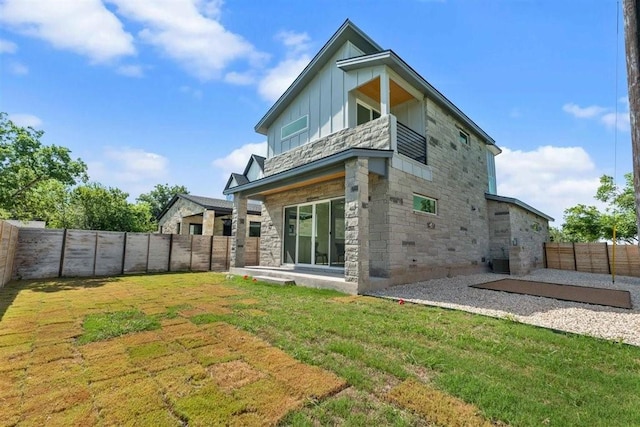 501 E Burton St, Manor, TX 78653 - rear view of house with board and batten siding, stone siding, a patio area, and a fenced backyard