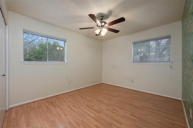 empty room with ceiling fan, light hardwood / wood-style flooring, and a textured ceiling