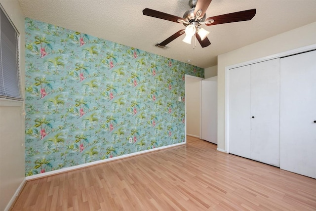 unfurnished bedroom with a closet, ceiling fan, a textured ceiling, and light hardwood / wood-style flooring