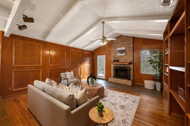 living room with vaulted ceiling with beams, a textured ceiling, dark hardwood / wood-style floors, wooden walls, and a fireplace