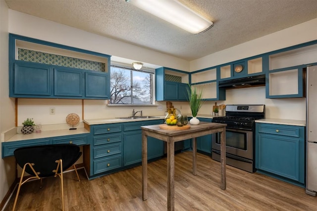 kitchen with sink, dark wood-type flooring, blue cabinetry, stainless steel appliances, and a textured ceiling