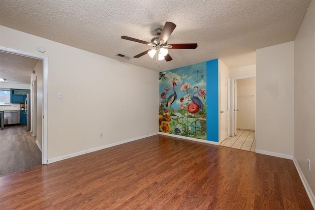 unfurnished room with ceiling fan, a textured ceiling, and light wood-type flooring