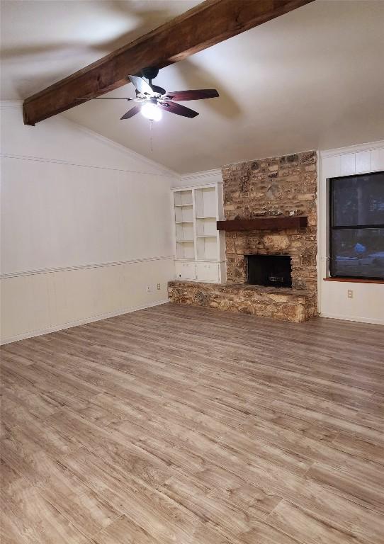 unfurnished living room with hardwood / wood-style floors, a fireplace, lofted ceiling with beams, and ceiling fan