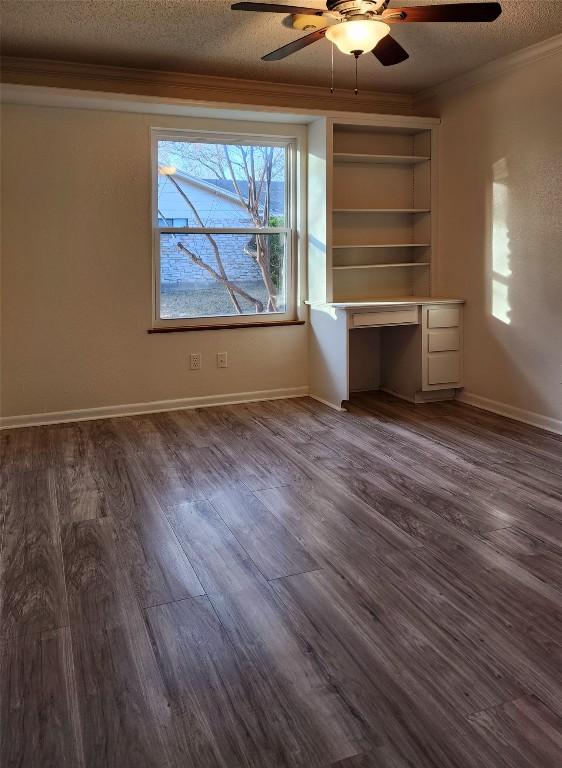 unfurnished bedroom with crown molding, dark wood-type flooring, built in desk, and a textured ceiling