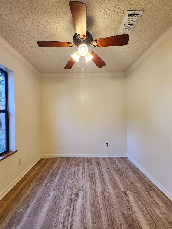 2000 Donna Dr, Taylor, TX 76574 - empty room with a textured ceiling, wood finished floors, ceiling fan, crown molding, and baseboards