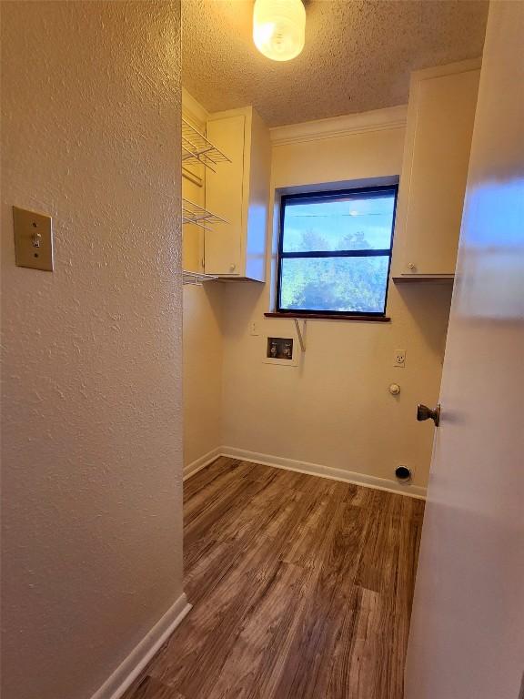 laundry area with hardwood / wood-style flooring, crown molding, cabinets, washer hookup, and a textured ceiling