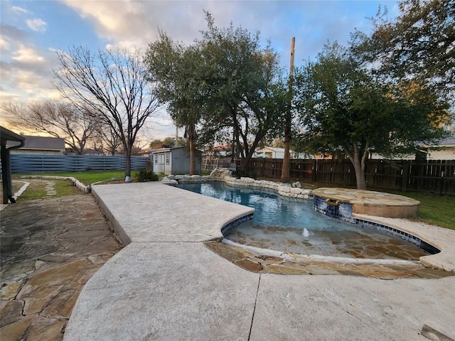 pool at dusk featuring a patio area, pool water feature, and a storage unit