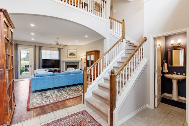 stairway featuring sink, ceiling fan, and a high ceiling