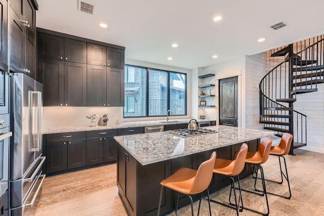 19217 Lost Tree Cv, Spicewood, TX 78669 - kitchen with appliances with stainless steel finishes, light wood-style flooring, a kitchen island, recessed lighting, and light stone countertops