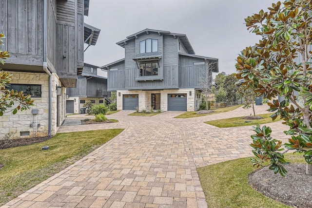 19217 Lost Tree Cv, Spicewood, TX 78669 - view of front of home featuring decorative driveway, an attached garage, stone siding, a balcony, and a front lawn