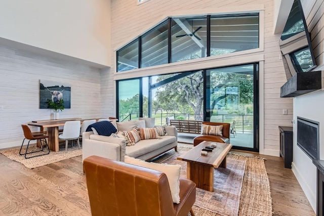19217 Lost Tree Cv, Spicewood, TX 78669 - living room featuring a towering ceiling, wood finished floors, healthy amount of natural light, wood walls, and a fireplace