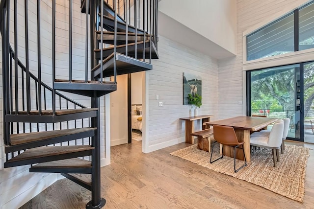 19217 Lost Tree Cv, Spicewood, TX 78669 - dining area with stairway, a towering ceiling, wood finished floors, and wood walls