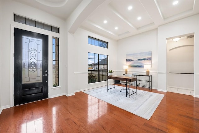 entrance foyer featuring hardwood / wood-style flooring, a high ceiling, coffered ceiling, and beam ceiling