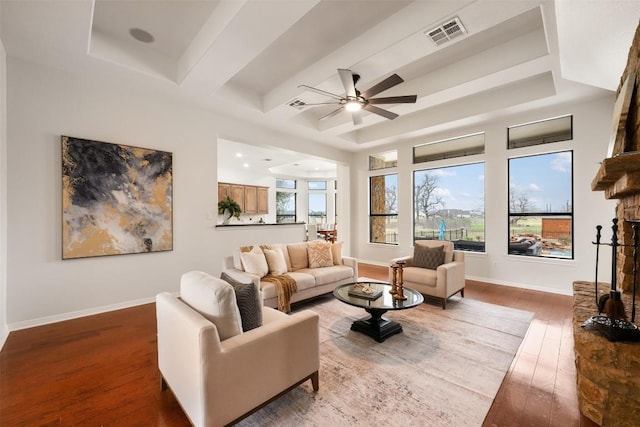 living room featuring dark wood-type flooring, a healthy amount of sunlight, a fireplace, and beam ceiling