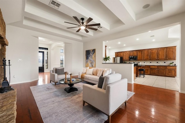 living room featuring a tray ceiling, light hardwood / wood-style flooring, and ceiling fan