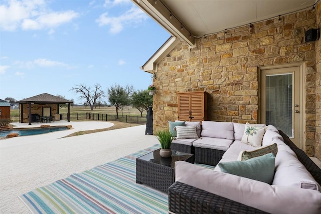 view of patio / terrace featuring a fenced in pool, a gazebo, and an outdoor living space with a fireplace