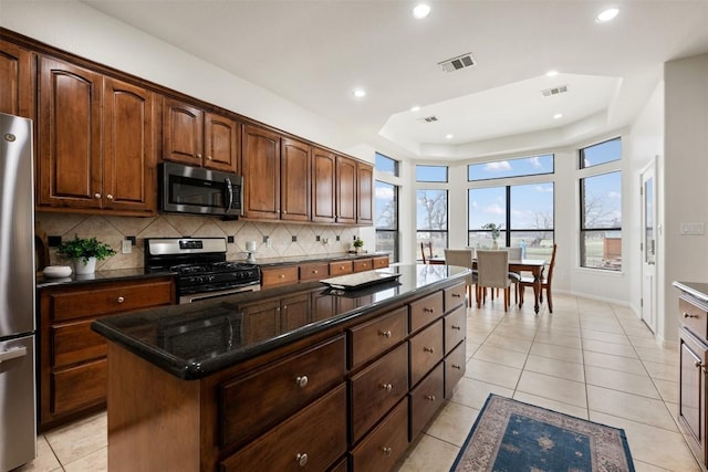 kitchen featuring stainless steel appliances, a center island, light tile patterned floors, and backsplash