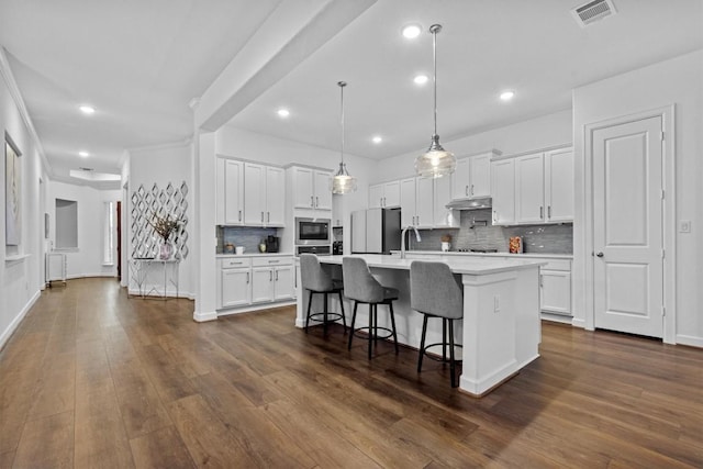 872 Wild Pecan Loop, Buda, TX 78610 - kitchen with stainless steel microwave, freestanding refrigerator, under cabinet range hood, light countertops, and decorative backsplash
