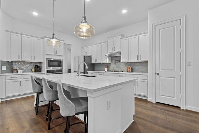 872 Wild Pecan Loop, Buda, TX 78610 - kitchen featuring stainless steel microwave, under cabinet range hood, wall oven, backsplash, and recessed lighting
