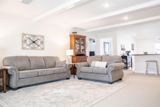 carpeted living room featuring beamed ceiling