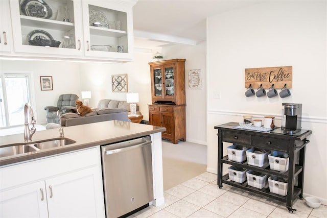 kitchen with white cabinetry, stainless steel dishwasher, sink, and light tile patterned floors