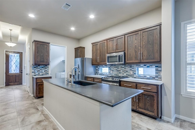 kitchen with dark brown cabinetry, appliances with stainless steel finishes, sink, and an island with sink