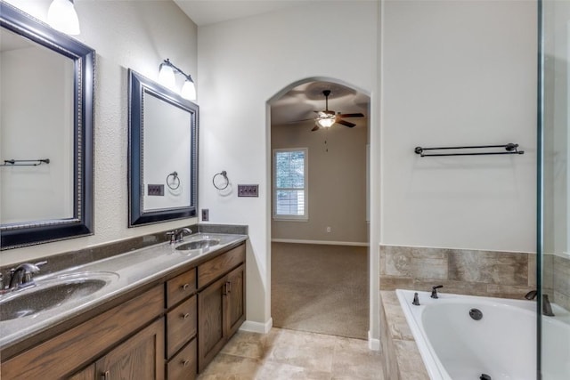 bathroom featuring ceiling fan, vanity, tile patterned floors, and tiled tub