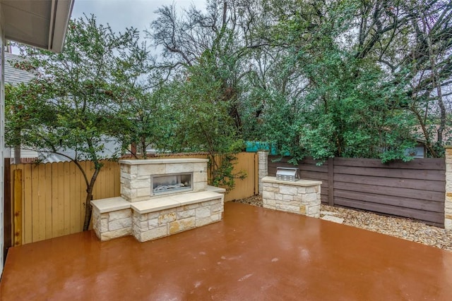 view of patio with area for grilling and an outdoor stone fireplace