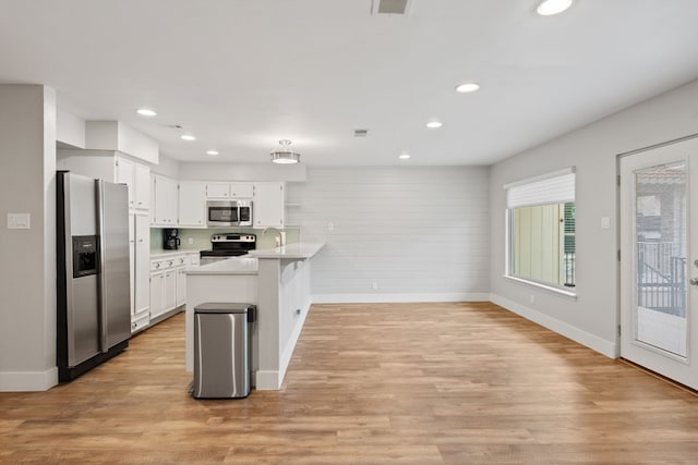 kitchen featuring sink, a breakfast bar area, white cabinetry, light hardwood / wood-style flooring, and stainless steel appliances