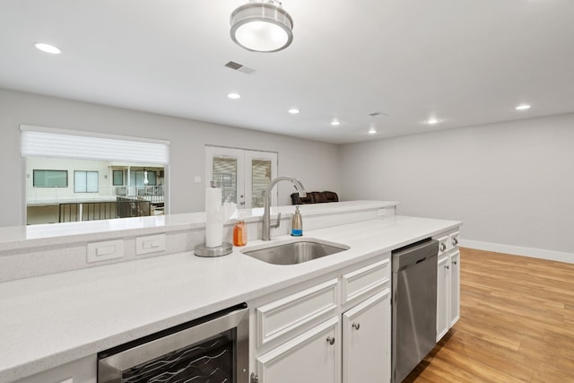 kitchen featuring sink, dishwasher, white cabinetry, french doors, and beverage cooler