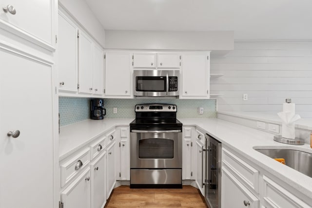 kitchen with tasteful backsplash, appliances with stainless steel finishes, beverage cooler, and white cabinets