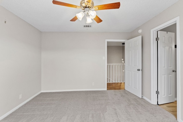 unfurnished bedroom featuring ceiling fan, light carpet, and a textured ceiling