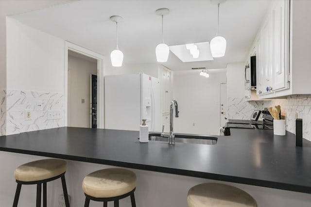 kitchen featuring sink, stove, hanging light fixtures, white cabinetry, and white refrigerator with ice dispenser