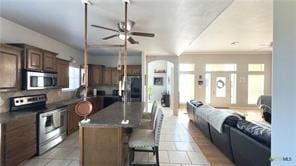 kitchen with ceiling fan, stainless steel appliances, a center island, and a breakfast bar area