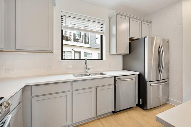 2050 Lohmans Spur Rd Unit 102, Lakeway, TX 78734 - kitchen featuring appliances with stainless steel finishes, light wood finished floors, backsplash, gray cabinets, and light countertops