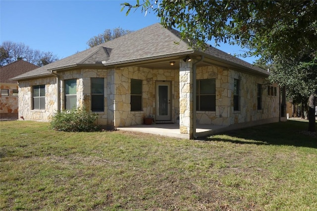 rear view of property featuring a patio area, stone siding, a lawn, and a shingled roof