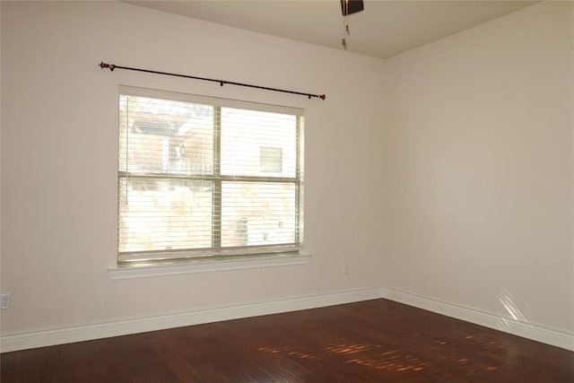 empty room featuring a wealth of natural light, baseboards, and wood finished floors