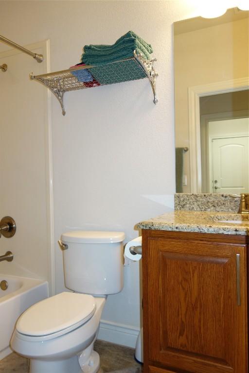 full bath featuring toilet, vanity, baseboards, and washtub / shower combination