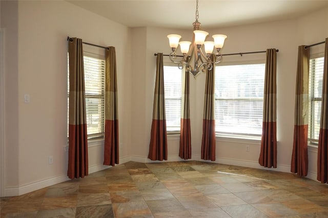 unfurnished dining area with a notable chandelier, baseboards, and a wealth of natural light