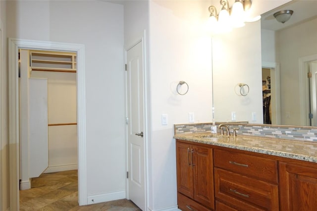 bathroom featuring vanity, a walk in closet, and backsplash