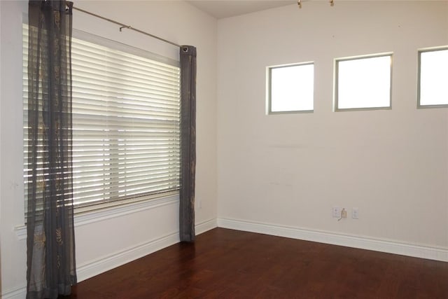 unfurnished room with plenty of natural light, wood finished floors, and baseboards