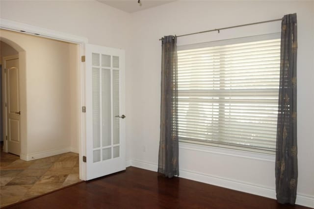 unfurnished bedroom with baseboards and arched walkways