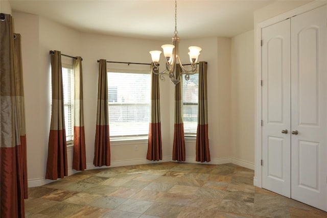 unfurnished dining area featuring baseboards and an inviting chandelier