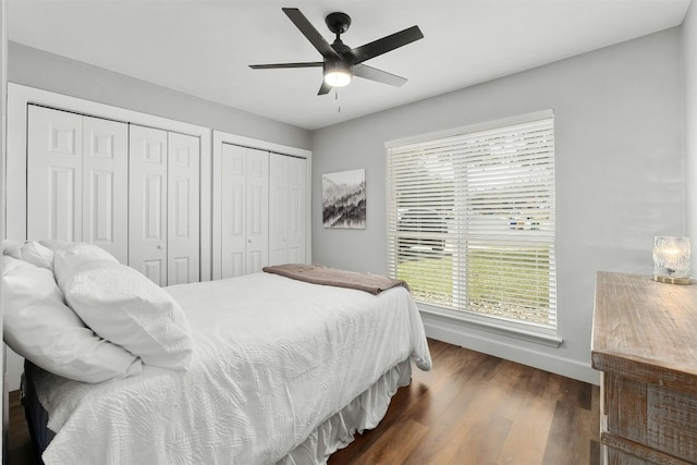 10113 Quail Hutch Dr, Austin, TX 78758 - bedroom featuring two closets, baseboards, dark wood-type flooring, and ceiling fan