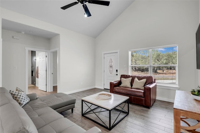 living room with light wood-style floors, ceiling fan, baseboards, and high vaulted ceiling