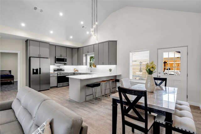 1514 Green Valley Ln, Granite Shoals, TX 78654 - kitchen featuring stainless steel appliances, gray cabinets, a peninsula, open floor plan, and a kitchen breakfast bar