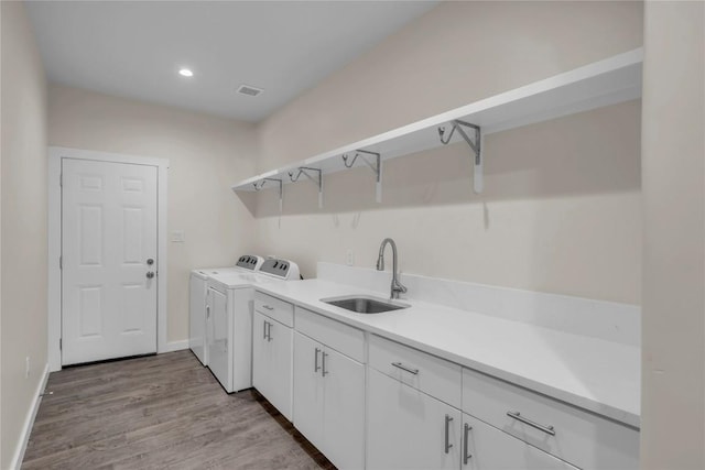 laundry room featuring washer and clothes dryer, recessed lighting, visible vents, a sink, and light wood-type flooring