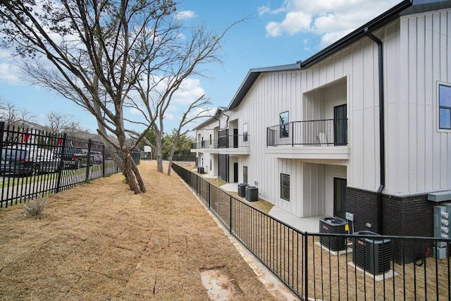 view of yard with central AC, a residential view, a fenced backyard, and a balcony