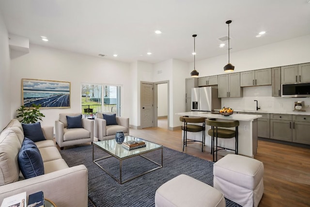 living area featuring a high ceiling, visible vents, wood finished floors, and recessed lighting