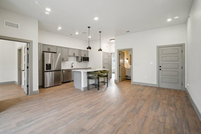 kitchen featuring a breakfast bar, a kitchen island, visible vents, light countertops, and appliances with stainless steel finishes